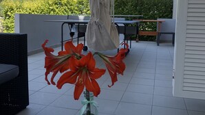 A patio area with a table, chairs, and a hanging macrame piece. - Apartmani Ana&Ita (Novalja)