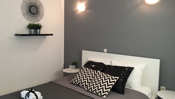 A modern bedroom with a bed, a wall-mounted air conditioner, a round mirror, and two wall sconces. - Apartmani Ana&Ita (Novalja)