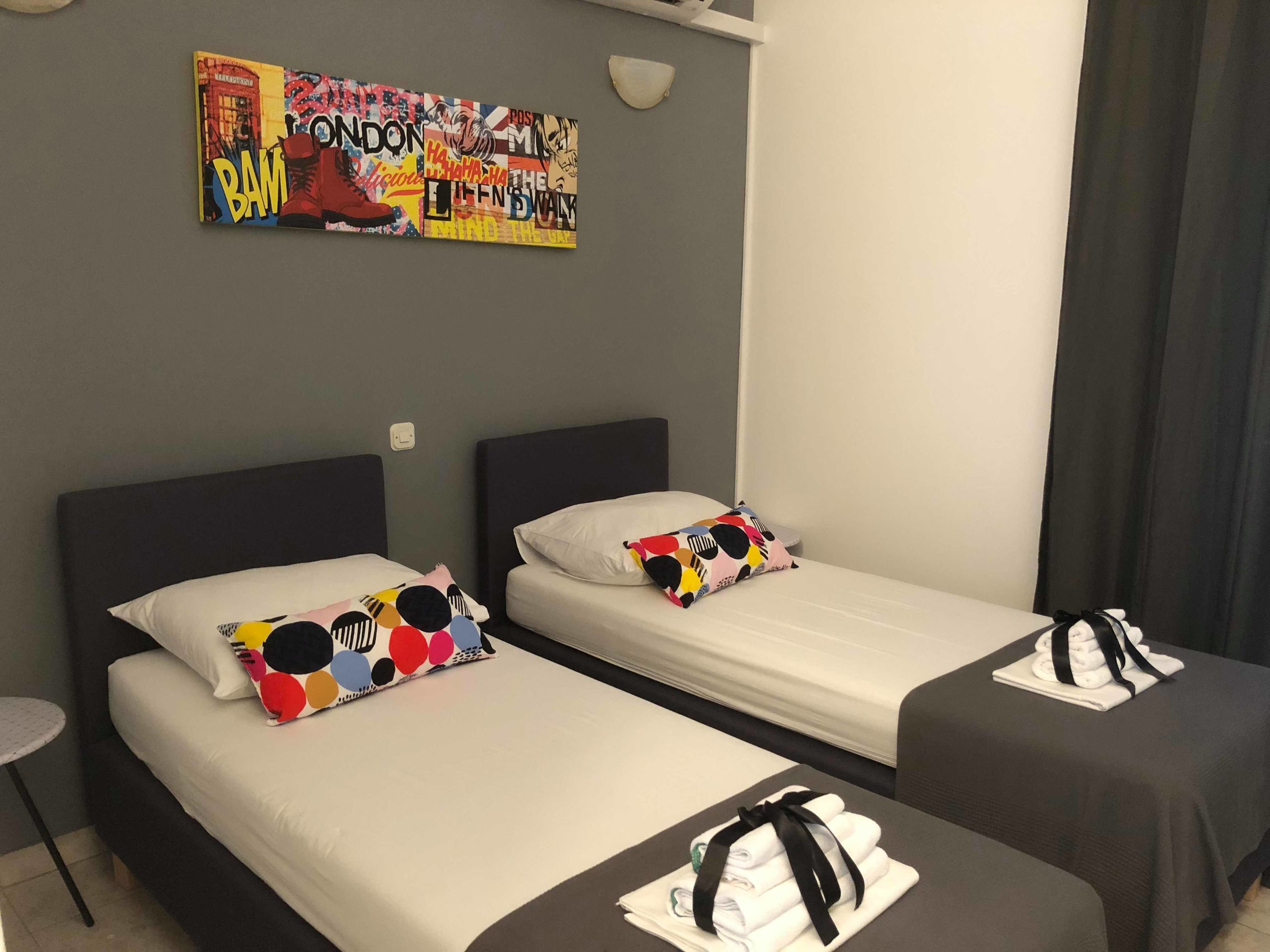 A hotel room with two beds, each with a pillow and a neatly folded towel on the bed.