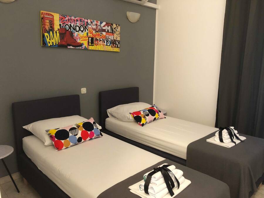A hotel room with two beds, each with a pillow and a neatly folded towel on the bed.