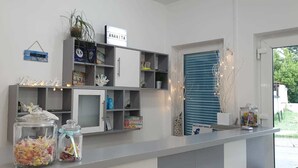 A reception area with a counter, shelves with various items, a 'Welcome' sign, and a 'Best Summer Holidays' poster. - Apartmani Ana&Ita (Novalja)