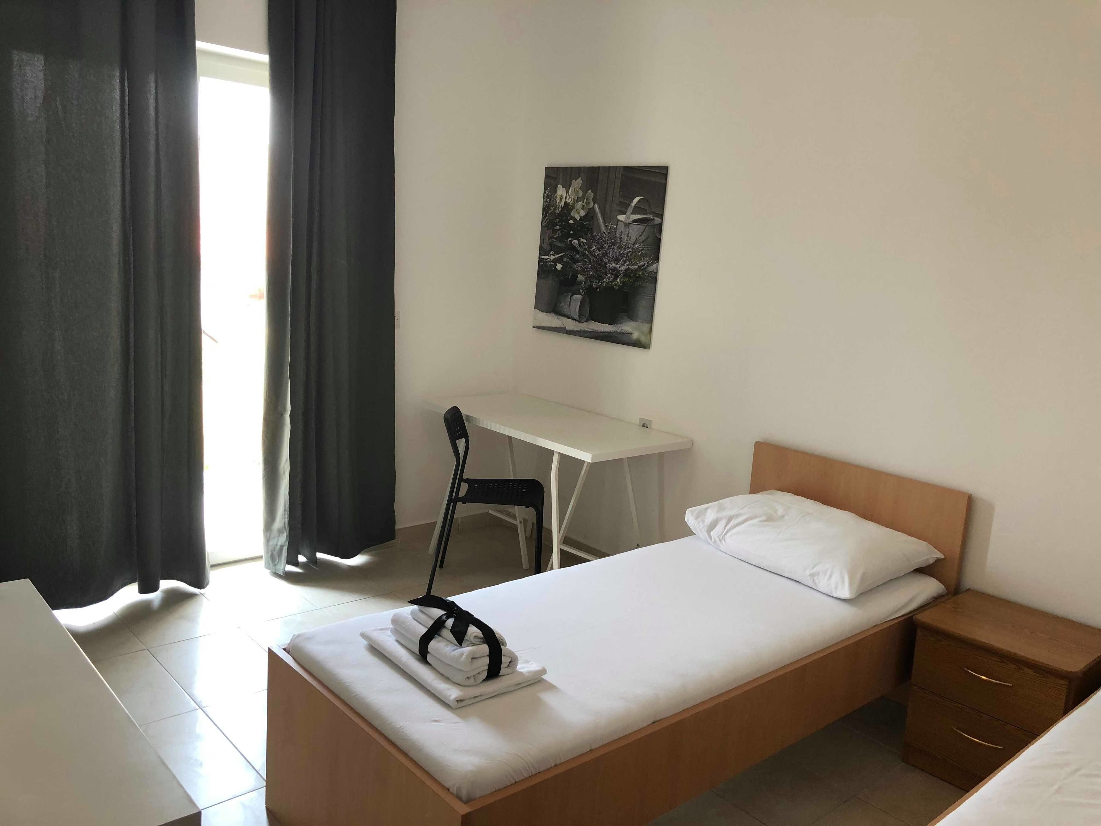 A neatly arranged bedroom with a bed, a desk, and a chair.