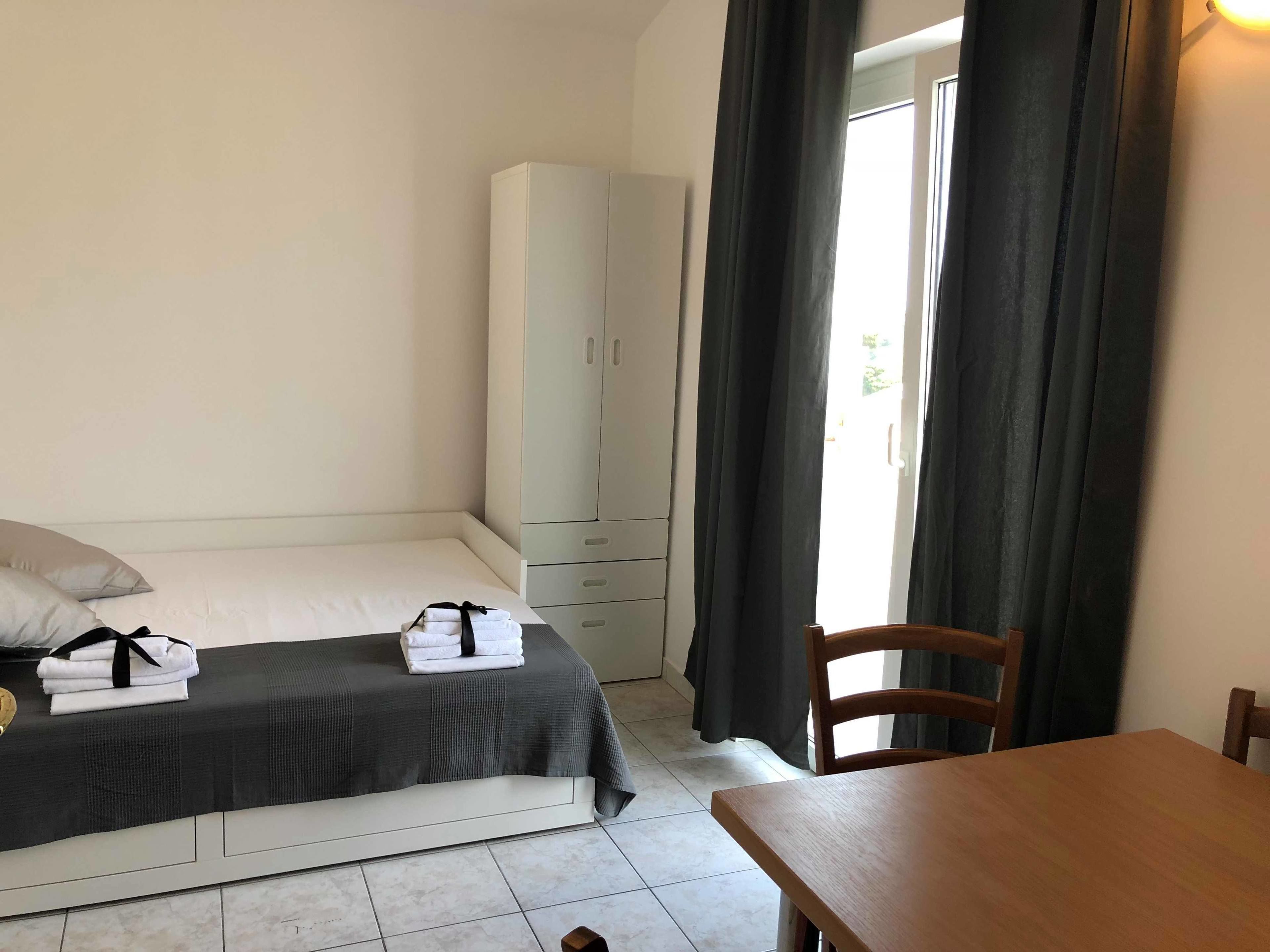Un dormitorio con cama, armario, mesa y silla.