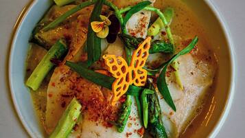 A bowl of fish with asparagus and a decorative flower.