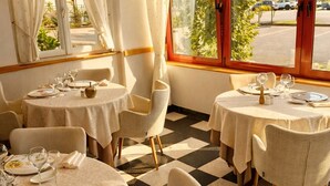 Un restaurante con mesas redondas, manteles blancos y sillas.