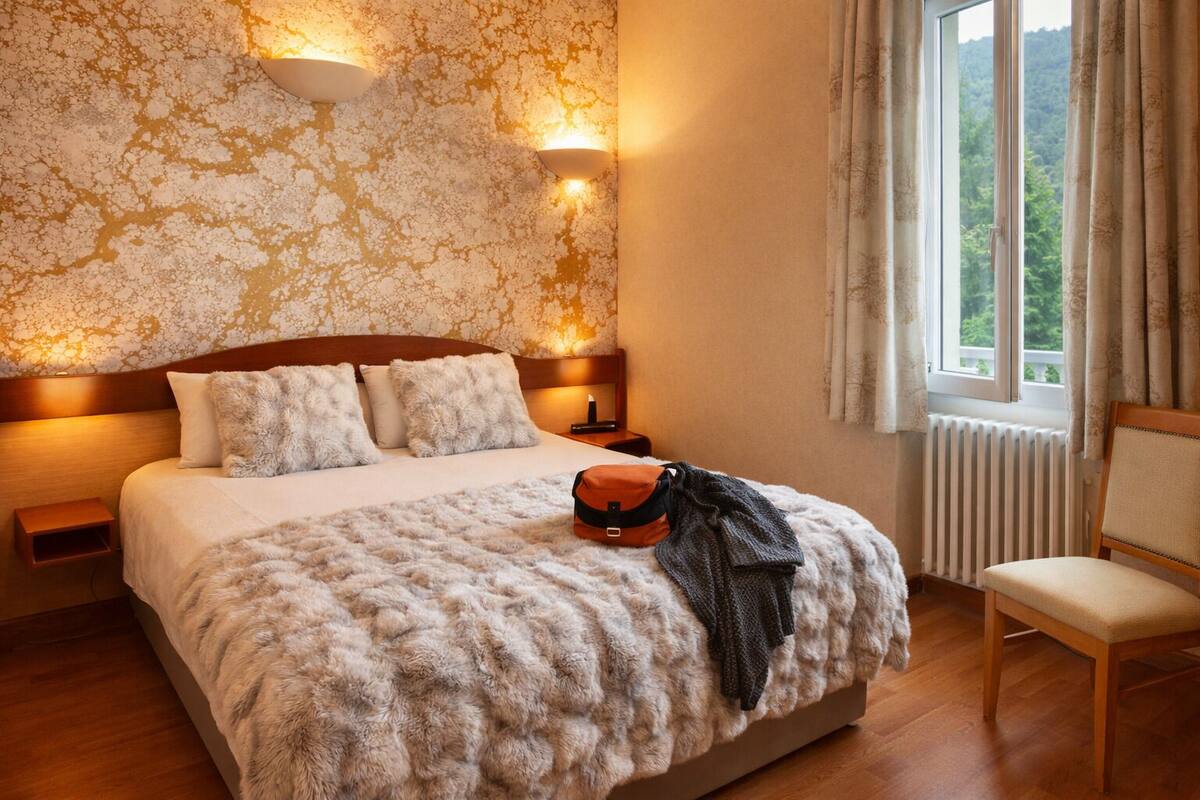Ein Schlafzimmer mit einem großen Bett, zwei Wandleuchten, einem fenster mit Vorhängen und einer Heizung.