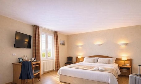 A hotel room with a bed, bedside tables, a desk with a chair, a television, and a window with curtains.. Logis Hôtel & Restaurant des Lacs