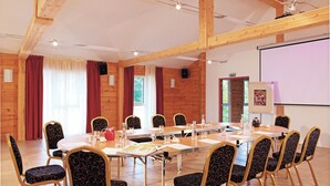 Un salón de conferencias con una larga mesa, varias sillas y una pantalla de proyector.