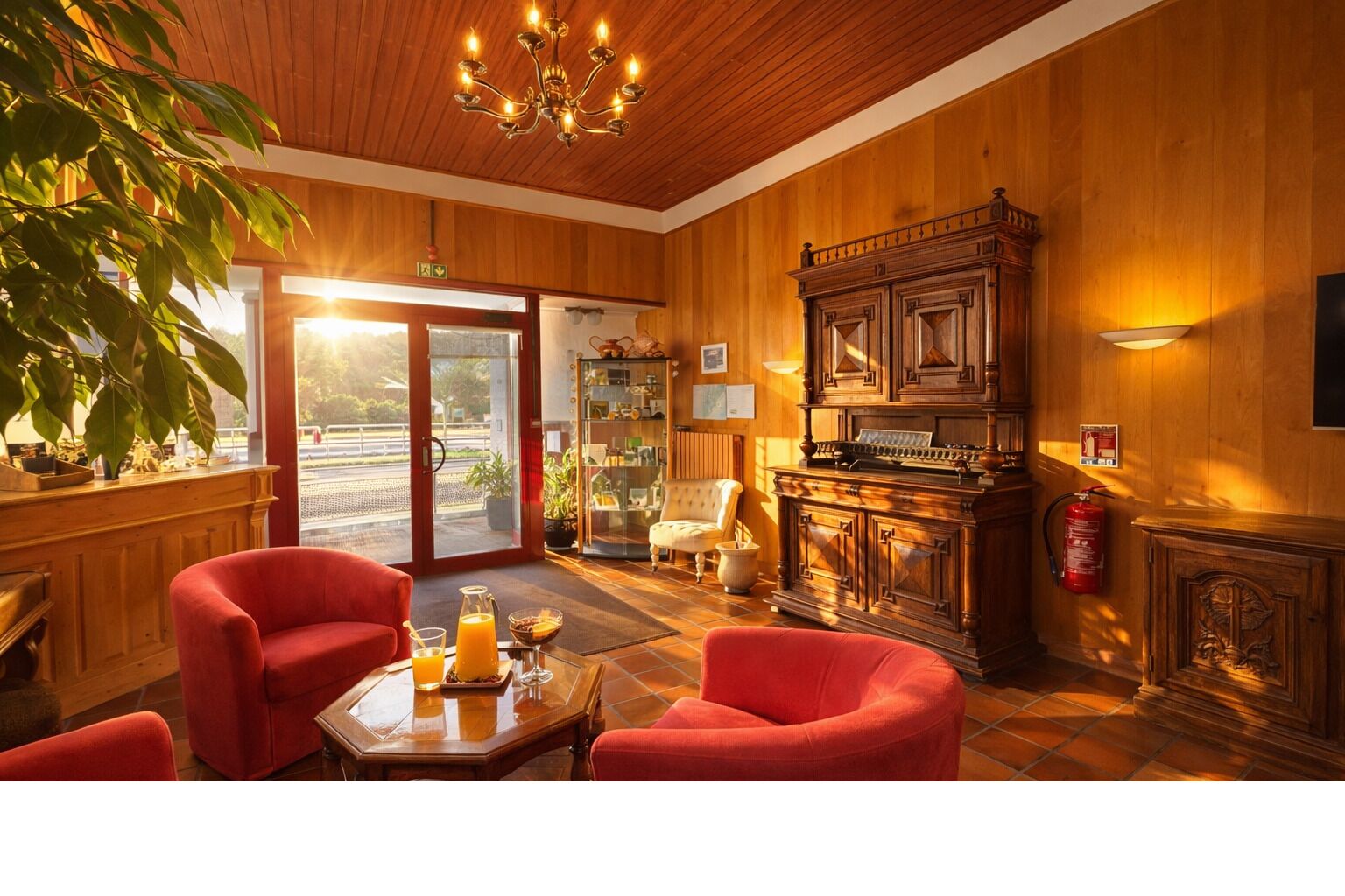 A wooden interior with a piano, red chairs, a glass table with drinks, and a large plant.