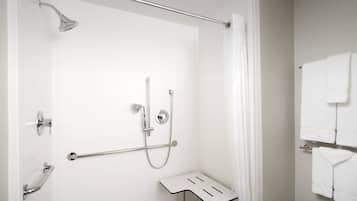 Un baño moderno con ducha, barras de apoyo y un perchero.