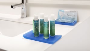 Un lavabo de salle de bain avec quatre flacons de lotion blanche et un porte-savon bleu.