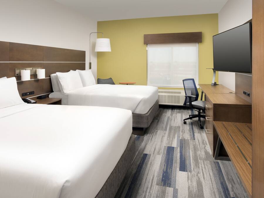 A hotel room with two beds, a desk, a TV, and a window with a view.