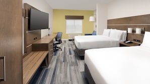 Une chambre d’hôtel avec un lit, un bureau, une chaise, une télévision et une fenêtre.