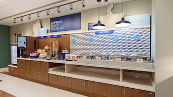 Espaço de buffet de café da manhã com seções identificadas para frutas, cereais e alimentos quentes.
