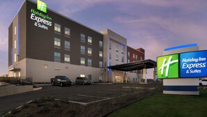 Een Holiday Inn Express & Suites gebouw met een parkeerplaats en een overdekte gang.
