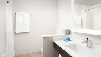 Un baño moderno con un lavamanos blanco, espejo y toallero.