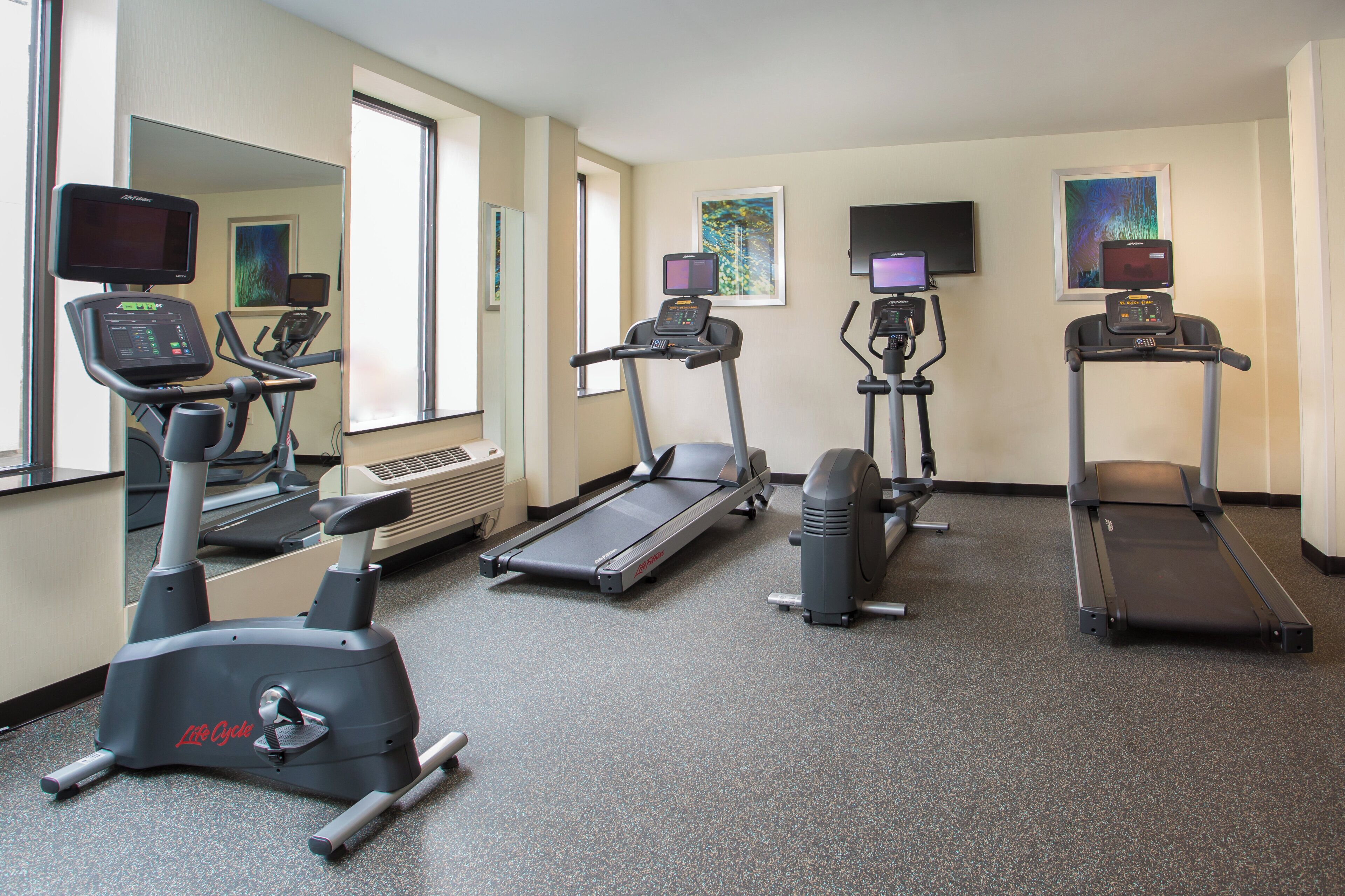 Une salle de remise en forme équipée de tapis de course, d’un vélo elliptique et d’un vélo d’appartement, tous dotés d’écrans numériques.