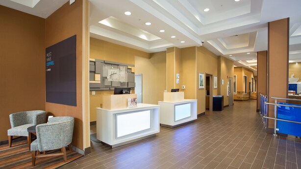 A hotel lobby with reception desks, seating area, and a modern ceiling design.