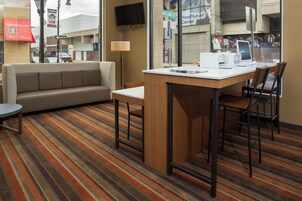 Habitación de hotel con sofá, una mesita y una silla. Se ve una ventana con vista a la calle.