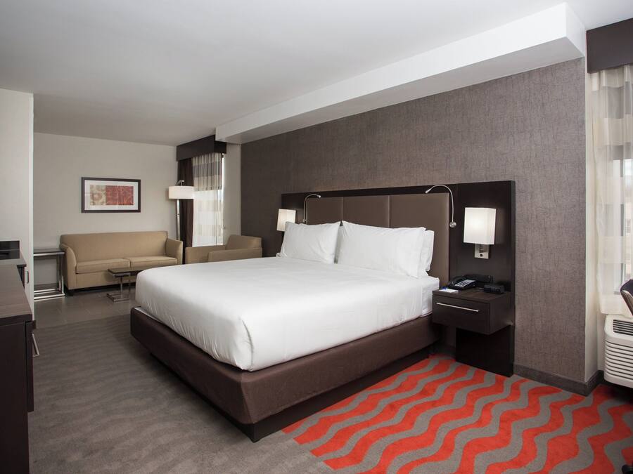 Una habitación de hotel con una cama grande, un escritorio, una silla, un sofá y un baño.