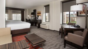 A hotel room with a bed, a desk, a chair, a small table, and a window with a view of a building. - Holiday Inn Express Springfield Downtown by IHG (Springfield)