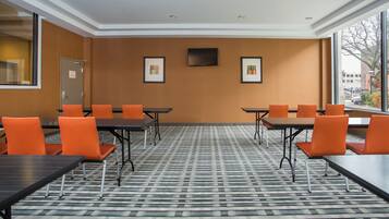A conference room with tables and chairs, a flat-screen TV, and framed artwork on the wall.