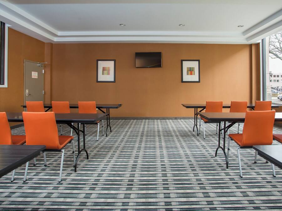 A conference room with tables and chairs, a flat-screen TV, and framed artwork on the wall.