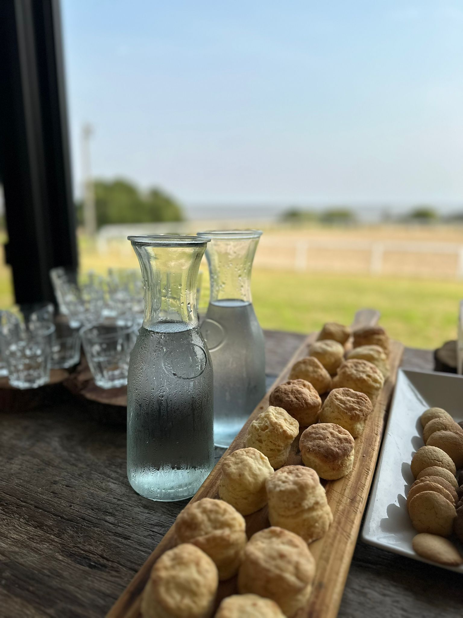 Ett träbord med en kanna vatten, glas och ett fat med bakverk.