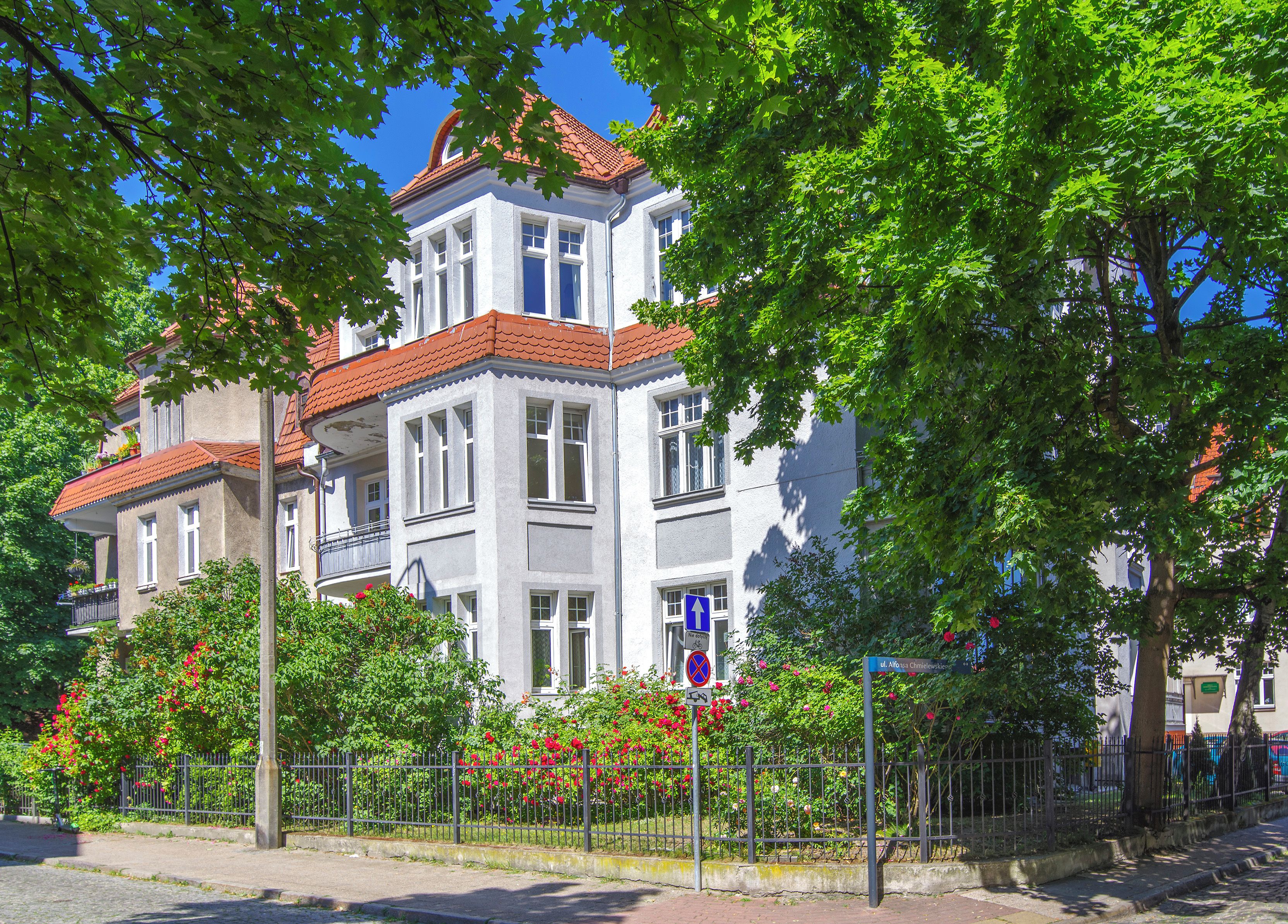 A multi-story building with a red-tiled roof, large windows, and a balcony.