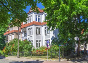 A multi-story building with a red-tiled roof, large windows, and a balcony.