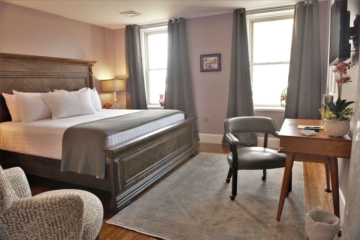 A neatly arranged bedroom with a large bed, a desk, and a chair.