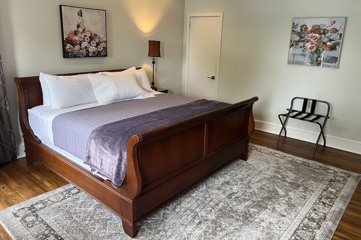 A neatly made bed with a wooden frame, a patterned bedspread, and a headboard.