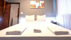 Une chambre d’hôtel avec un lit bien fait, une petite table de chevet avec une lampe et un tableau accroché au mur.