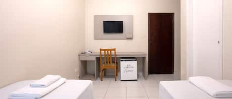 A small, clean room with two beds, a desk, a chair, a TV mounted on the wall, and a minibar.