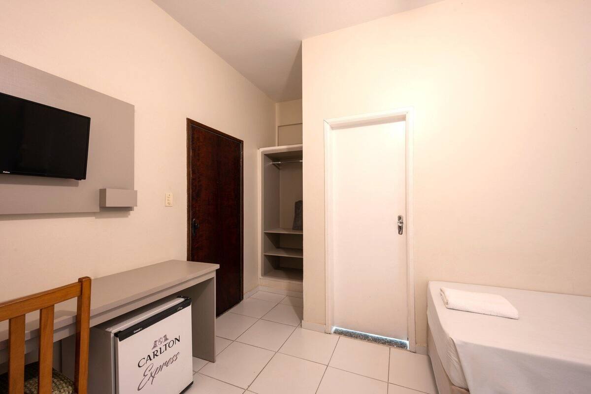 Ein Schlafzimmer mit Bett, Schreibtisch, Stuhl, Kleiderschrank und Fernseher an der Wand.