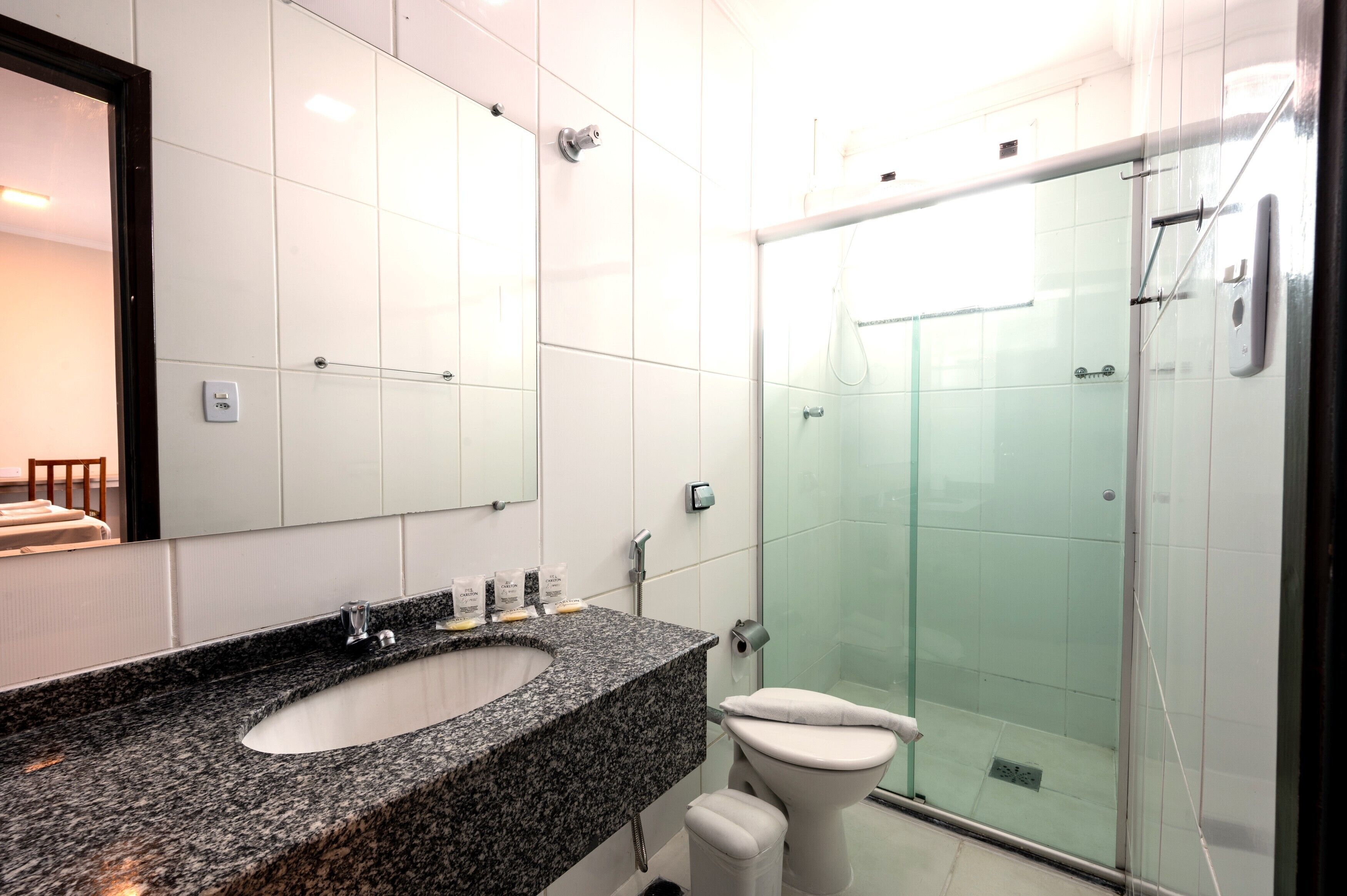 A modern bathroom with a granite sink, white toilet, and a glass-enclosed shower.