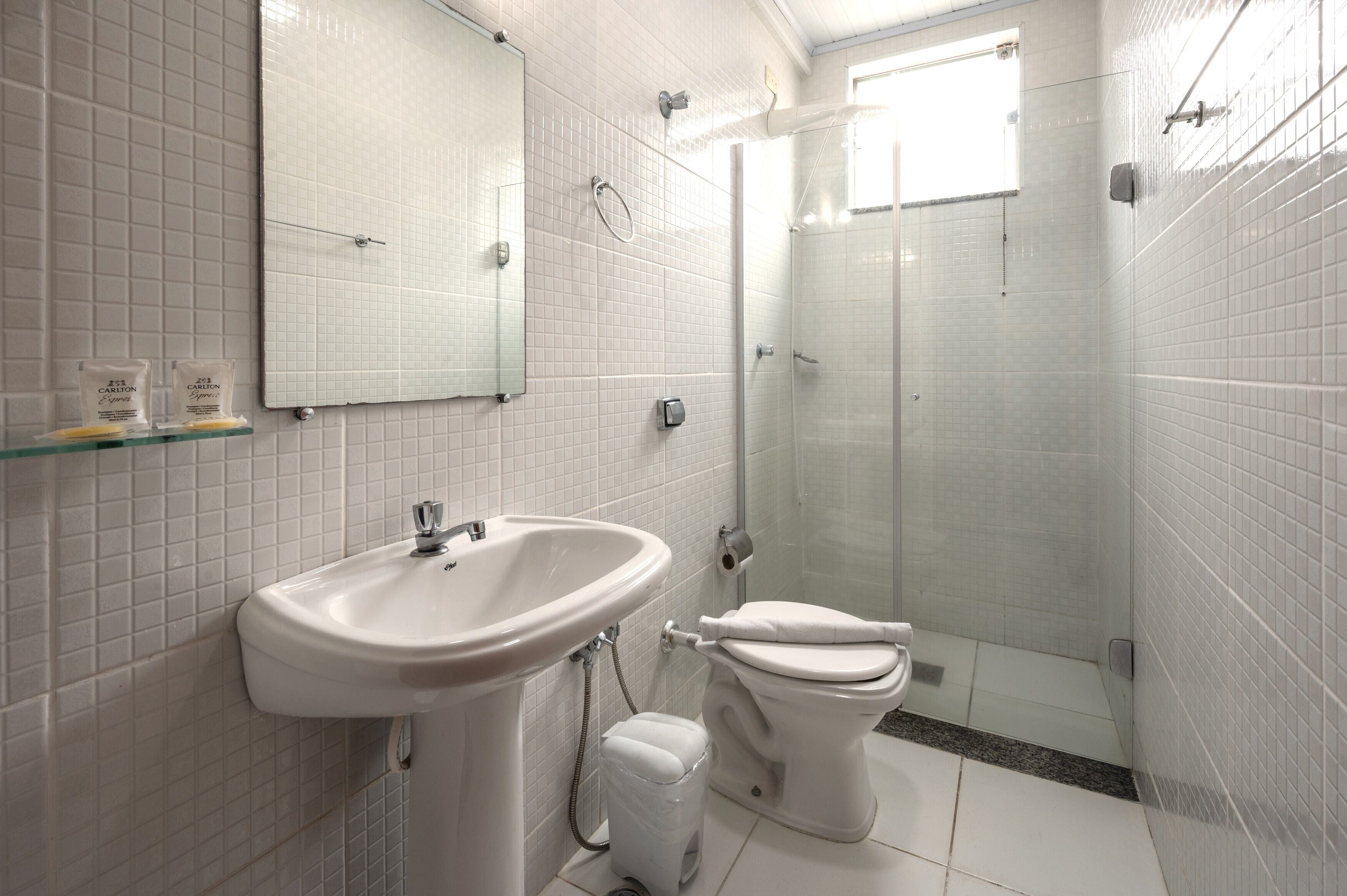 Une salle de bain équipée d’un lavabo, de toilettes et d’une douche à parois de verre.
