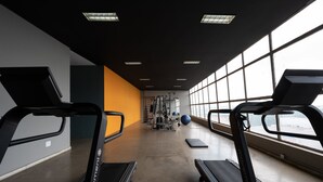 Une salle de sport équipée de tapis de course, de ballons d'exercice et d'appareils de musculation.