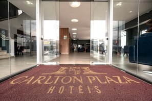 De ingang van Carlton Plaza Hotel met een rode loper en glazen deuren.