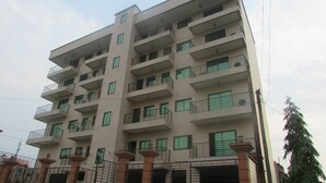Un edificio residencial de varios pisos, con balcones, techo plano y fachada sencilla.