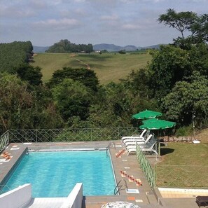 Una piscina al aire libre, sillones reclinables de piscina