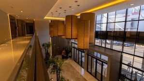 Un moderno vestíbulo de hotel con fachada de vidrio, una columna central y un suelo reflectante.