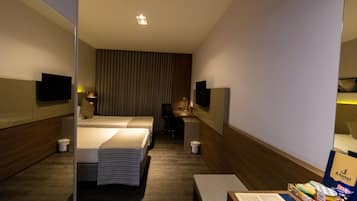 Una camera d'albergo con un letto, una scrivania, una sedia, una televisione e un minibar.