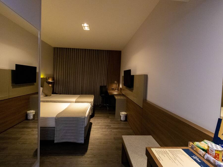 Una camera d'albergo con un letto, una scrivania, una sedia, una televisione e un minibar.