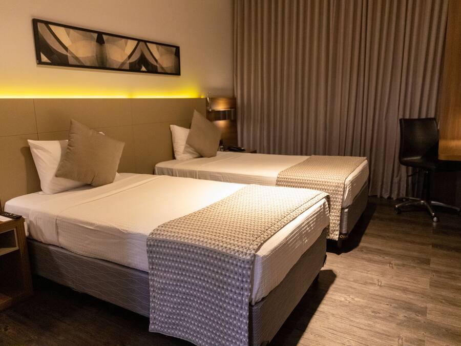 A hotel room with two beds, a desk, and a chair.