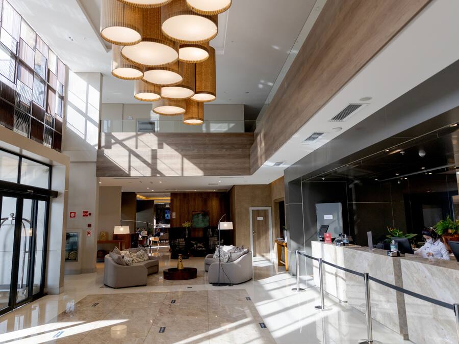 Un hall espacioso con techo alto, luminarias modernas y un mostrador de recepción.