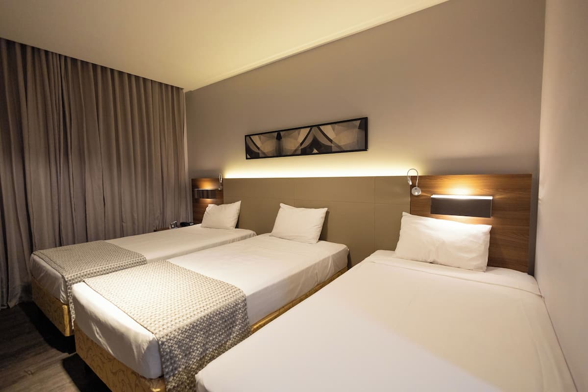 Una habitación de hotel con dos camas individuales, un ventanal con cortinas, una obra de arte colgada en la pared y lámparas de noche.