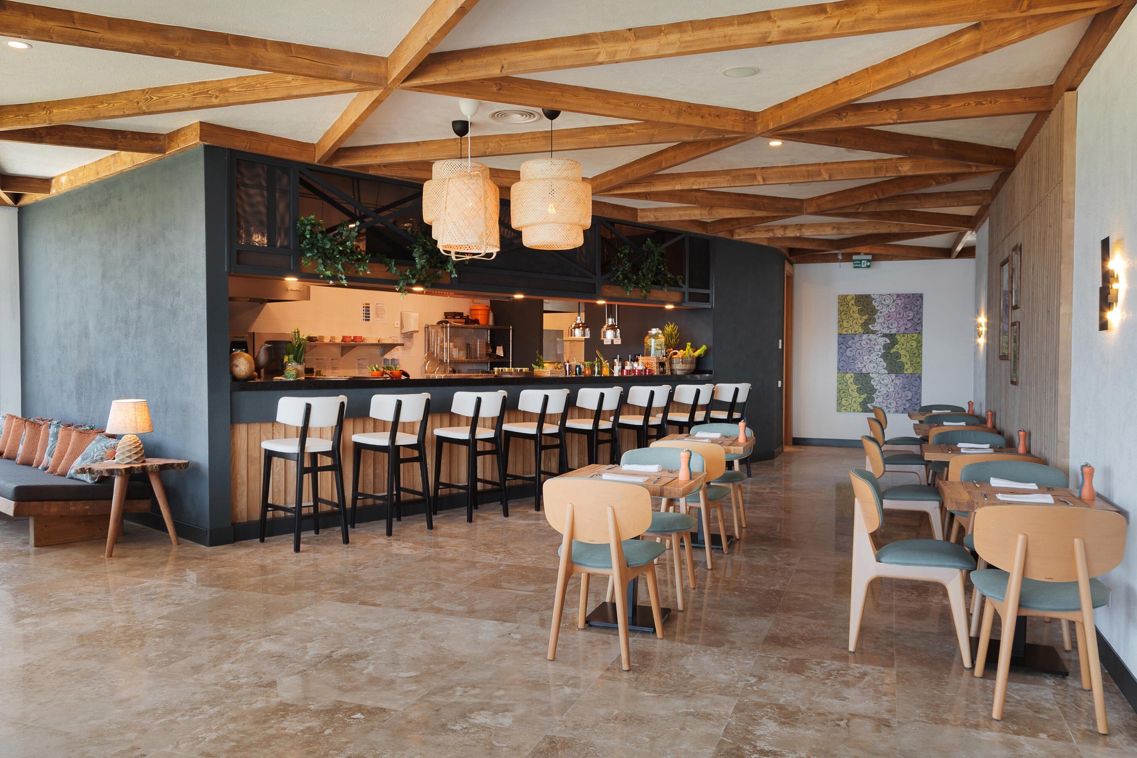 Un restaurant doté d'un bar, de poutres en bois au plafond et proposant différents types de sièges, notamment des tables et des chaises.