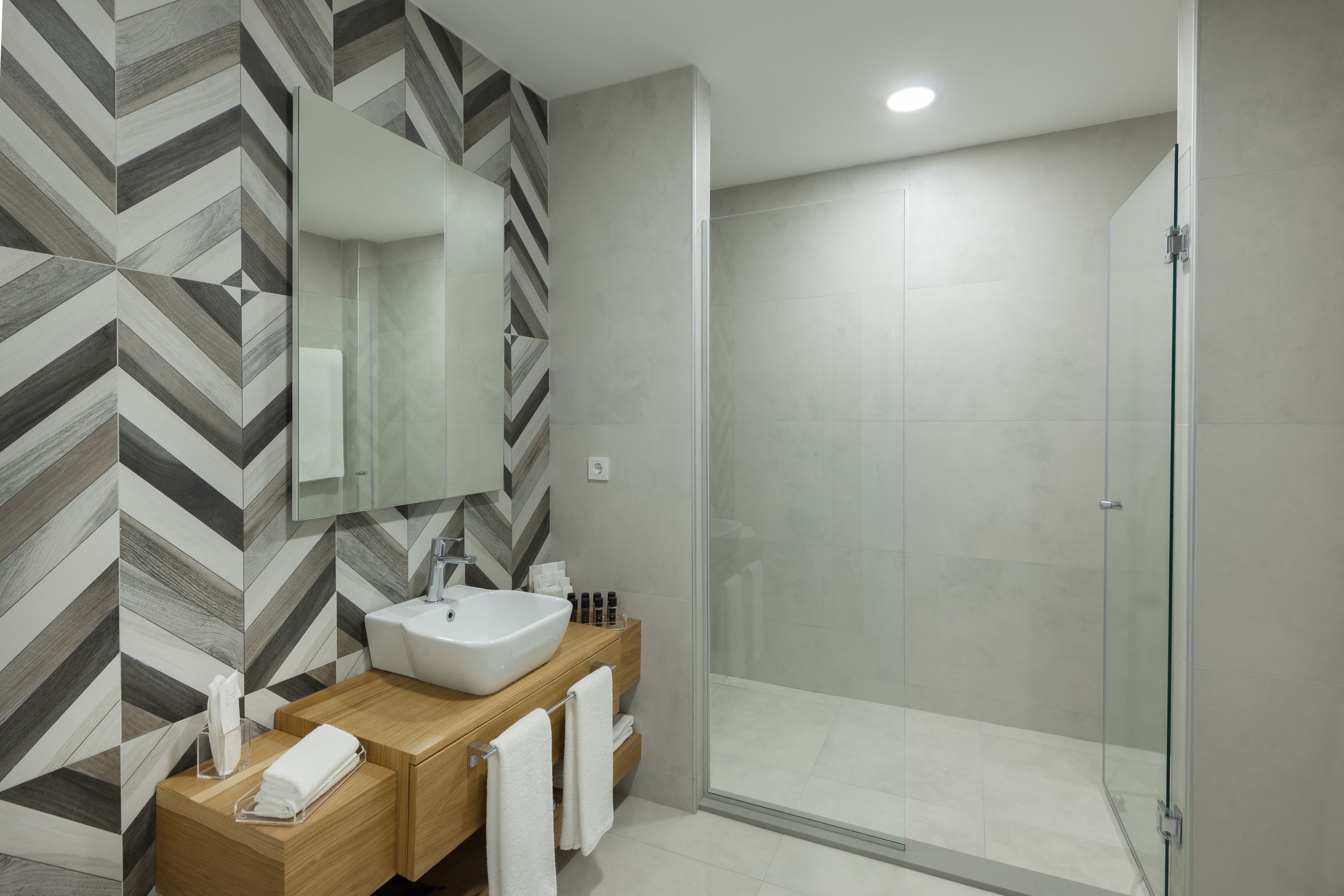 Un baño moderno con un espejo grande, un lavabo y una zona de ducha.