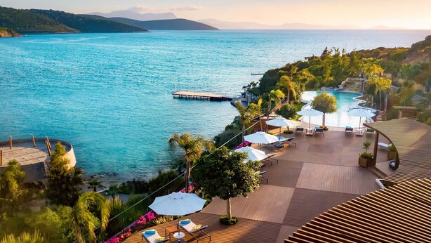 A resort with a pool area, lounge chairs, and a view of the sea. - Le Méridien Bodrum Beach Resort (Milas)